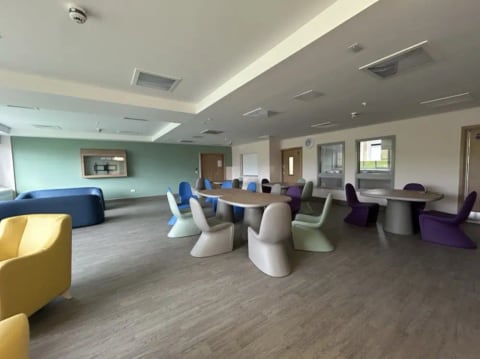 Bright communal room with sofas and moulded chairs
